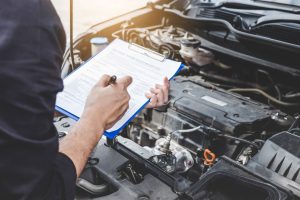 A service technician performing an inspection on a car's engine near Anderson, Indiana