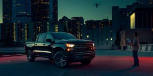 2025 Chevy Silverado 1500 parked in an urban setting at night, highlighting its bold design and modern features.