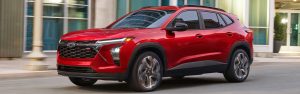 A red Chevrolet Trax SUV driving on a city street.