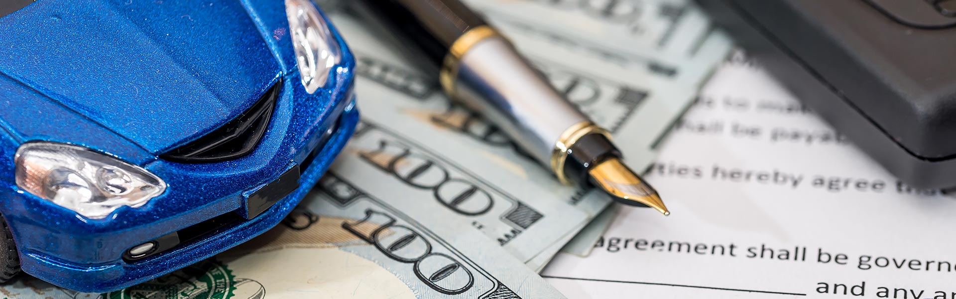 Blue car model with financing documents and pen on a table.