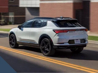 A white Chevrolet Equinox EV driving down a city street