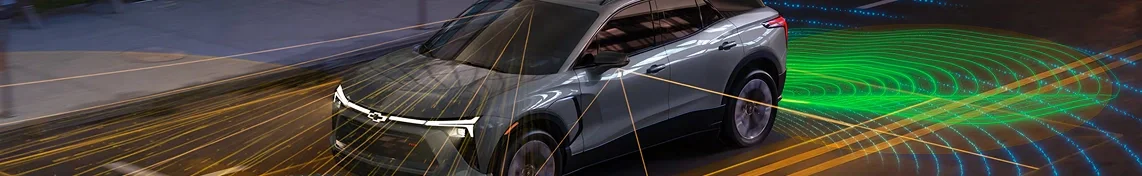 A gray Chevrolet EV on a road at dusk with illustrated camera and sensor beams around it