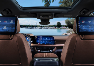 The cabin of a Chevrolet SUV from the rear seat, with a wide dashboard display and rear-seat entertainment screens