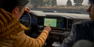 A driver touching a map on a Chevrolet center touchscreen while a passenger looks on