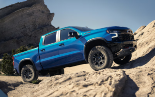 A blue Chevrolet Silverado pickup climbing over desert rocks