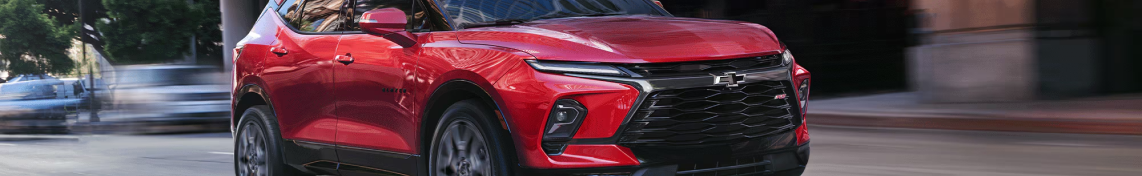 A red Chevrolet Blazer EV driving past a blurred city street