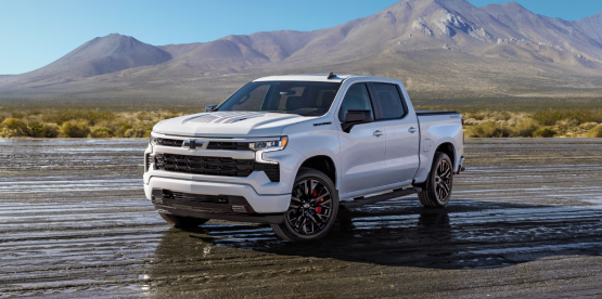 A white Chevrolet Silverado 1500 RST parked on a dry lake bed below mountains