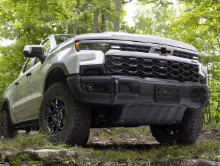A white Chevrolet Silverado 1500 ZR2 on a rocky trail in a green forest