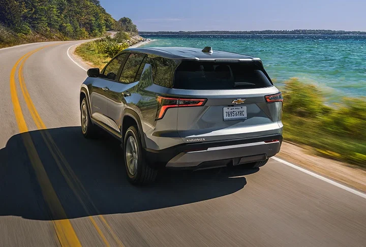 A gray Chevrolet Equinox driving along a curving coastal road