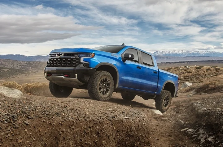 A blue Chevrolet Silverado ZR2 driving over rocky desert terrain
