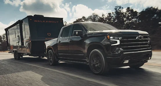 A black Chevrolet Silverado towing a camper trailer